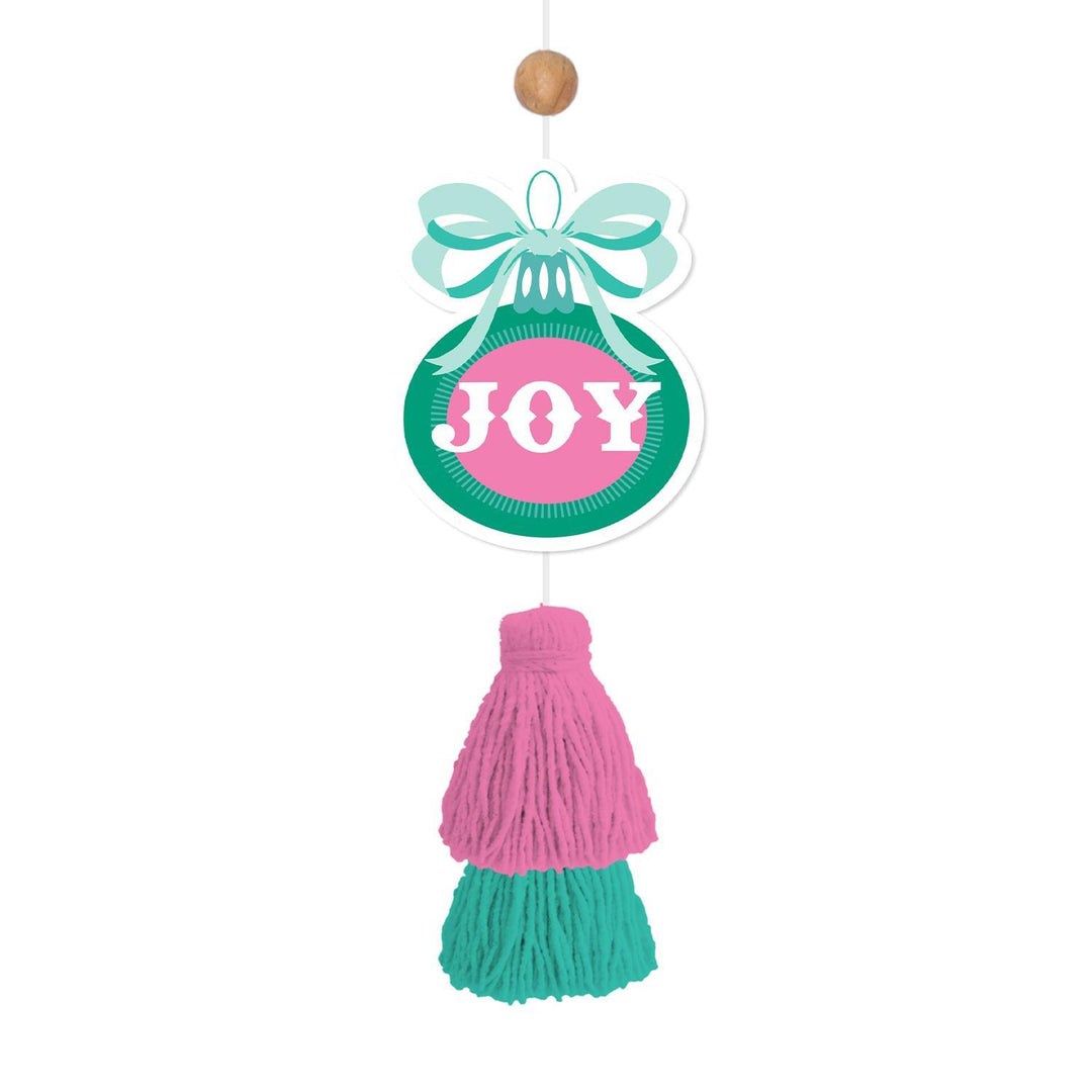 Ornament-shaped car air freshener with a light blue bow, a teal circular base with a pink “JOY” center, and a pink and teal yarn tassel.