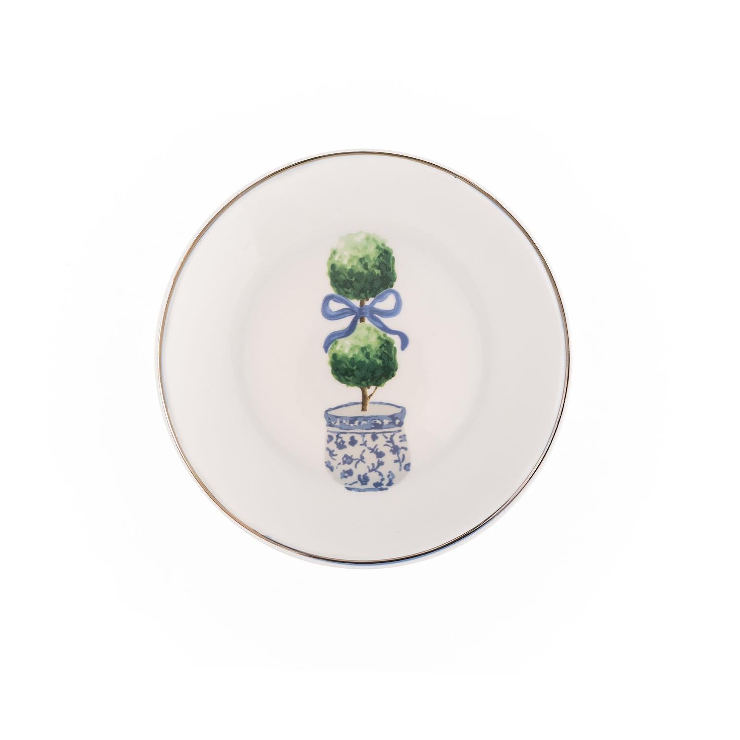 Explore the Topiary Appetizer Plate: white plate with a topiary tree and blue ribbon, in a blue and white patterned pot. Features a thin gold rim. Available size: 6.5 inches diameter.