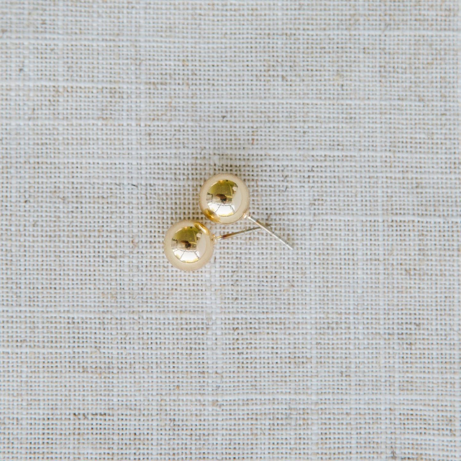 Grenada Earrings: Small, round gold stud earrings with hypoallergenic surgical steel posts. Available in one size.