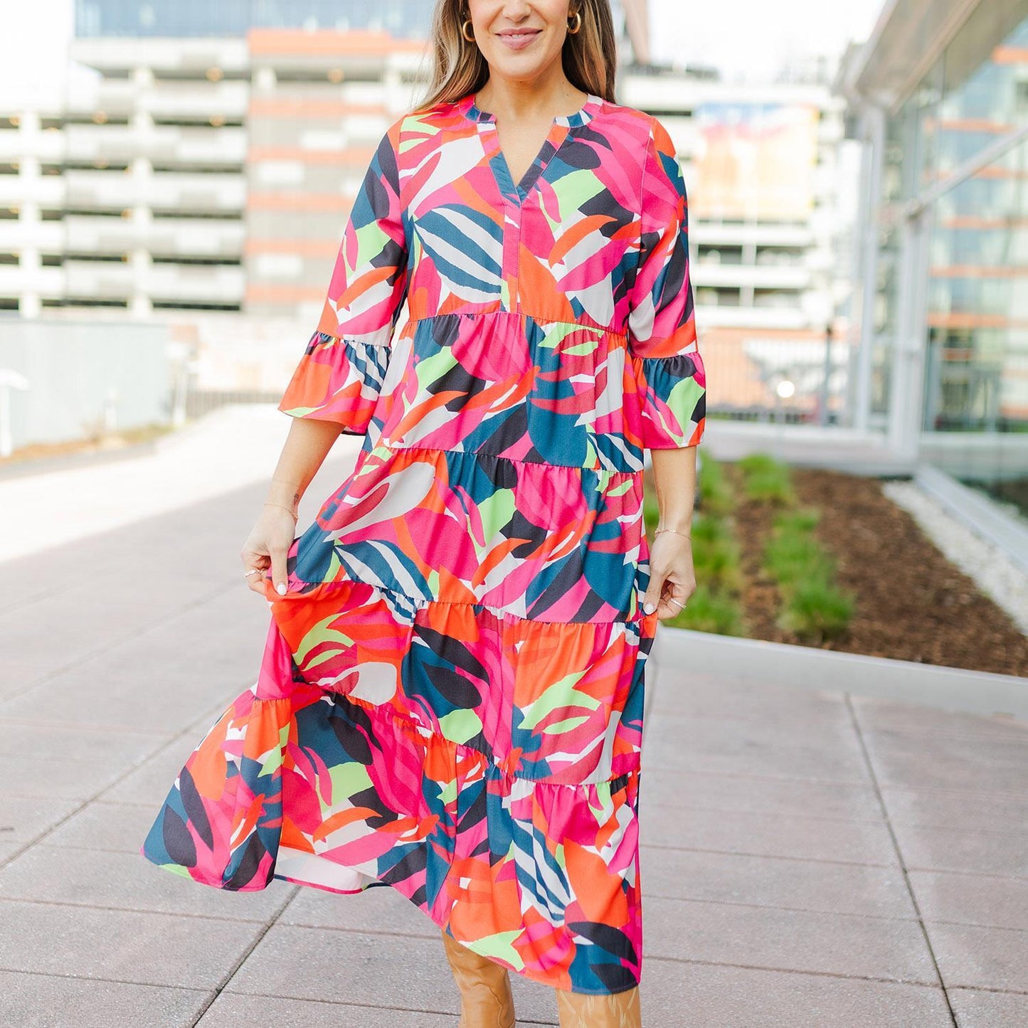 Benette Bombshell Blooms Dress: A must-have piece featuring vibrant shades of pink, red, blue, orange, and white in a colorful abstract pattern. Available sizes: S, M, L.