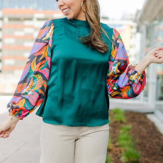 Stylish teal Melanie Top with vibrant, colorful patterned puffed sleeves. Sizes available: S, M, L, XL.