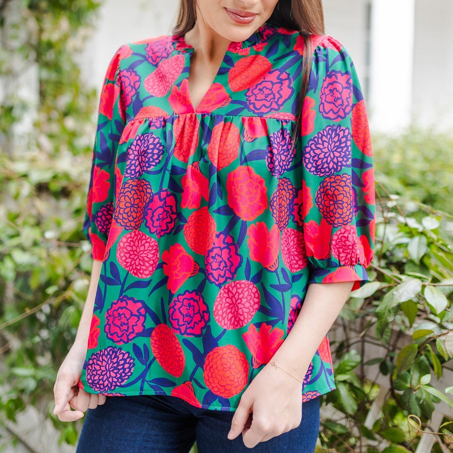 Vibrant V-neck blouse with red, pink, and purple floral patterns; gathered detailing. Sizes: S, M, L.