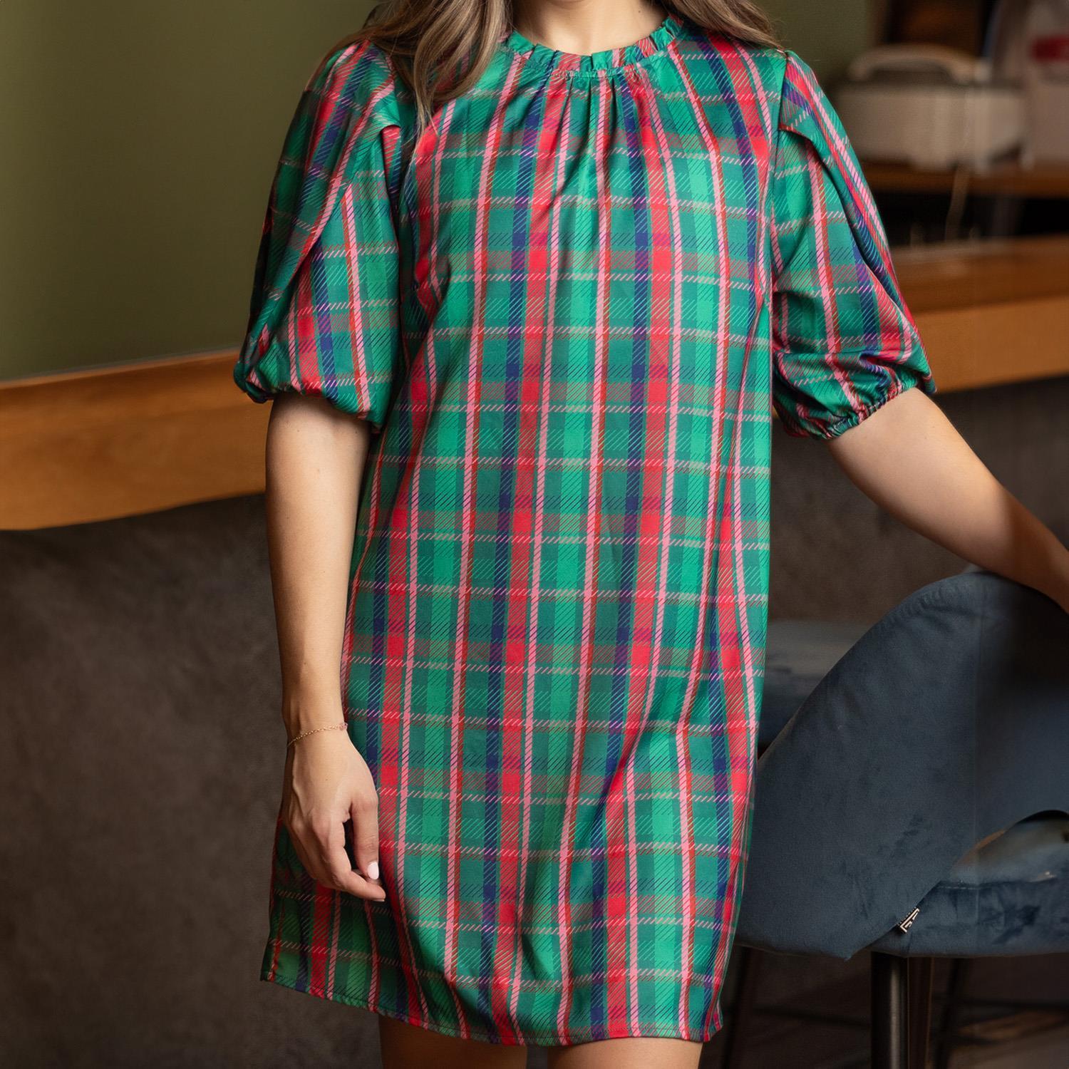 The Libby Dress showcases a green and pink plaid pattern with puff sleeves, perfect for festive events. Available in sizes XS to XL.