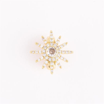 Gold starburst earring with central brown gemstone and sparkling spokes. Available in small, medium, and large sizes.
