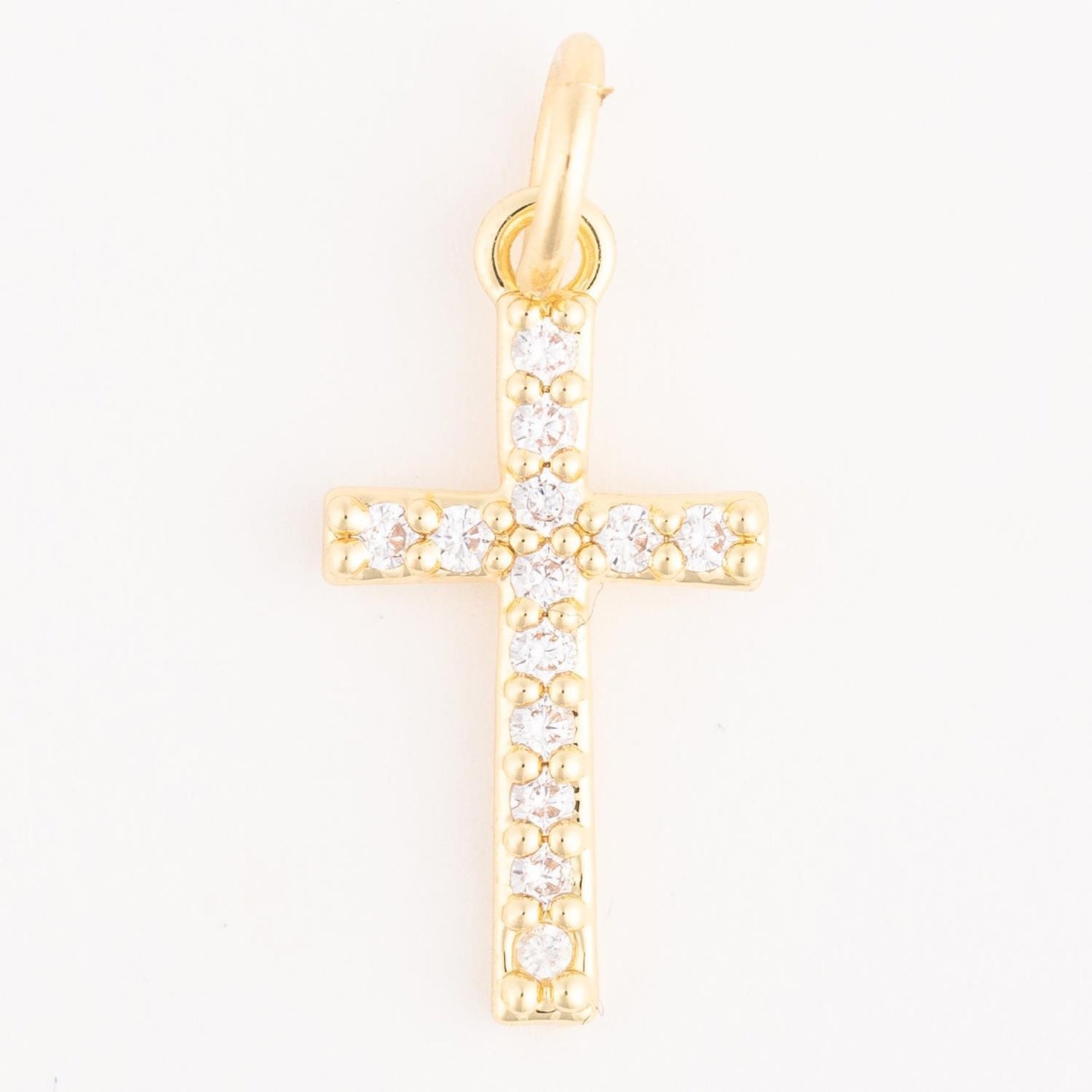 The Thea Charm Bar is an 18k gold plated necklace with a gold cross pendant set with small, round clear gemstones. Available in multiple sizes.