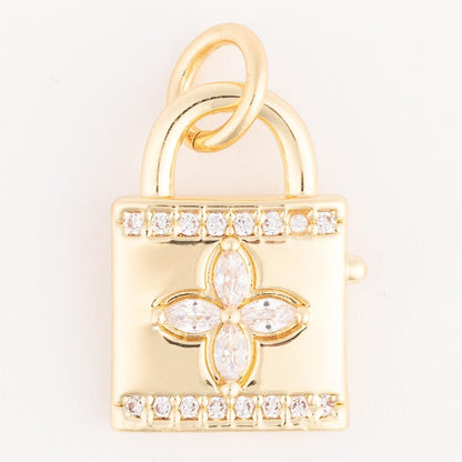 The Thea Charm Bar is a gold padlock charm with a central floral diamond motif and two rows of diamonds on the top and bottom. Hypoallergenic, fits any 18k gold plated necklace. Available sizes: Small, Medium, Large.