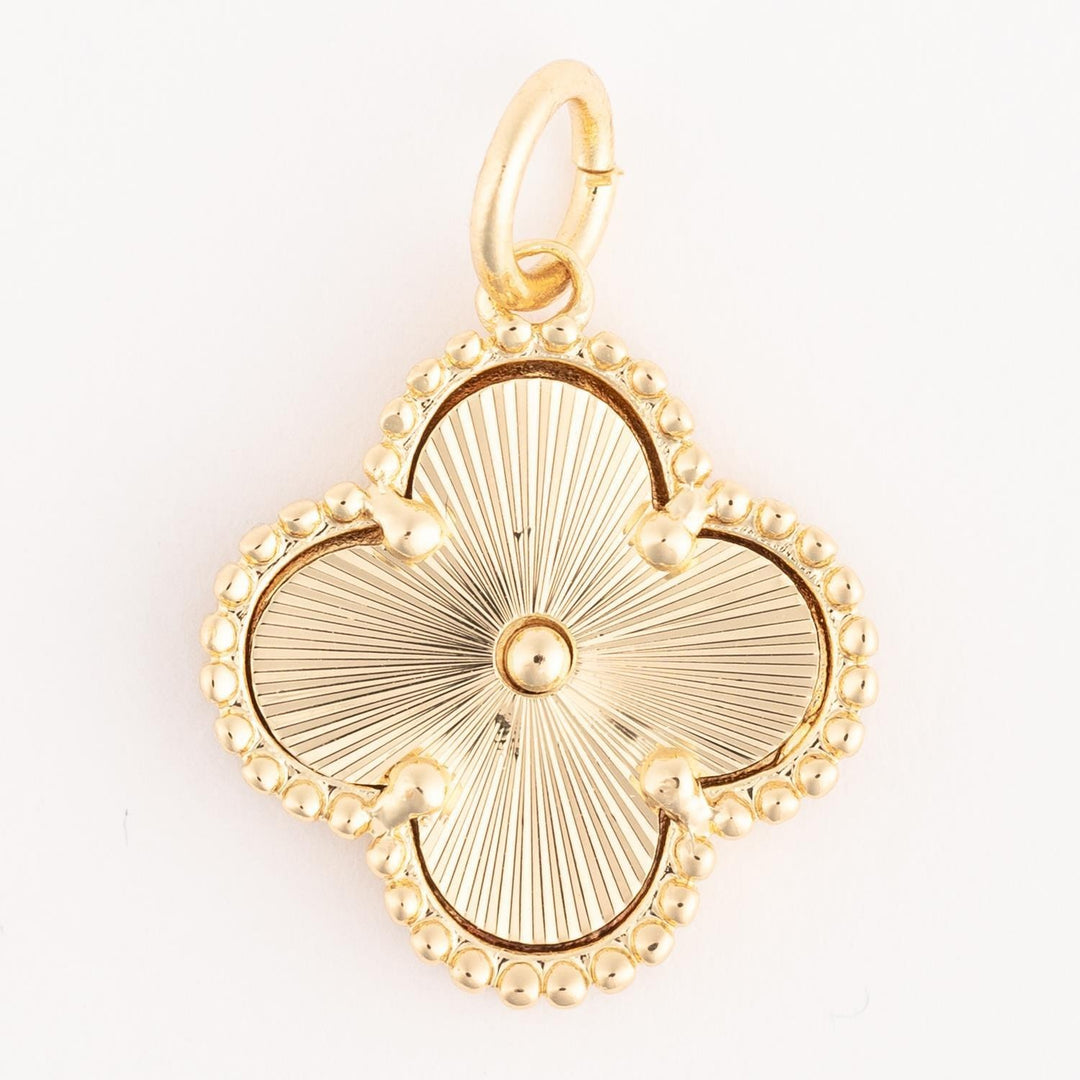 Gold clover-shaped pendant with beaded edge and sunburst center, finished in 18k gold plating. Hypoallergenic, includes a small loop for necklaces. Available sizes not specified.