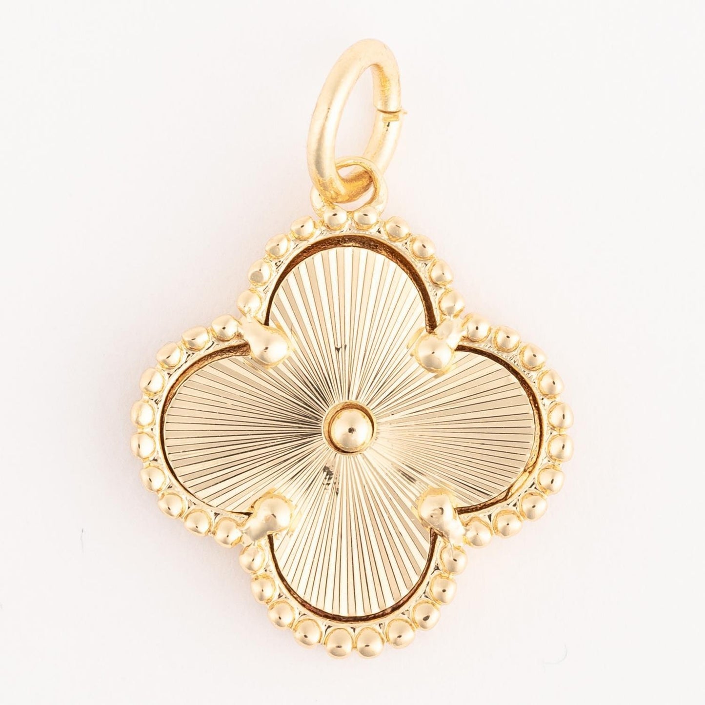 Gold clover-shaped pendant with beaded edge and sunburst center, finished in 18k gold plating. Hypoallergenic, includes a small loop for necklaces. Available sizes not specified.