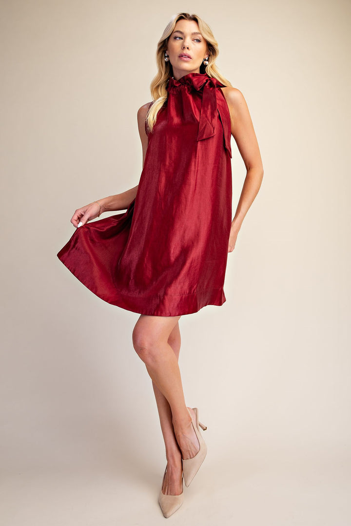 Camille Metallic Tie-Neck Dress: sleeveless, shiny red metallic fabric, statement tie-neck with large bow. Available in sizes XS-XL.