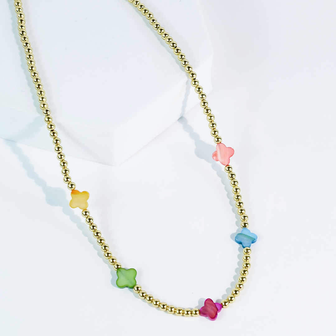 The Petal Pop Necklace by Treasure Jewels with gold and pastel flower beads in yellow, green, blue, pink, and red. Sizes available.
