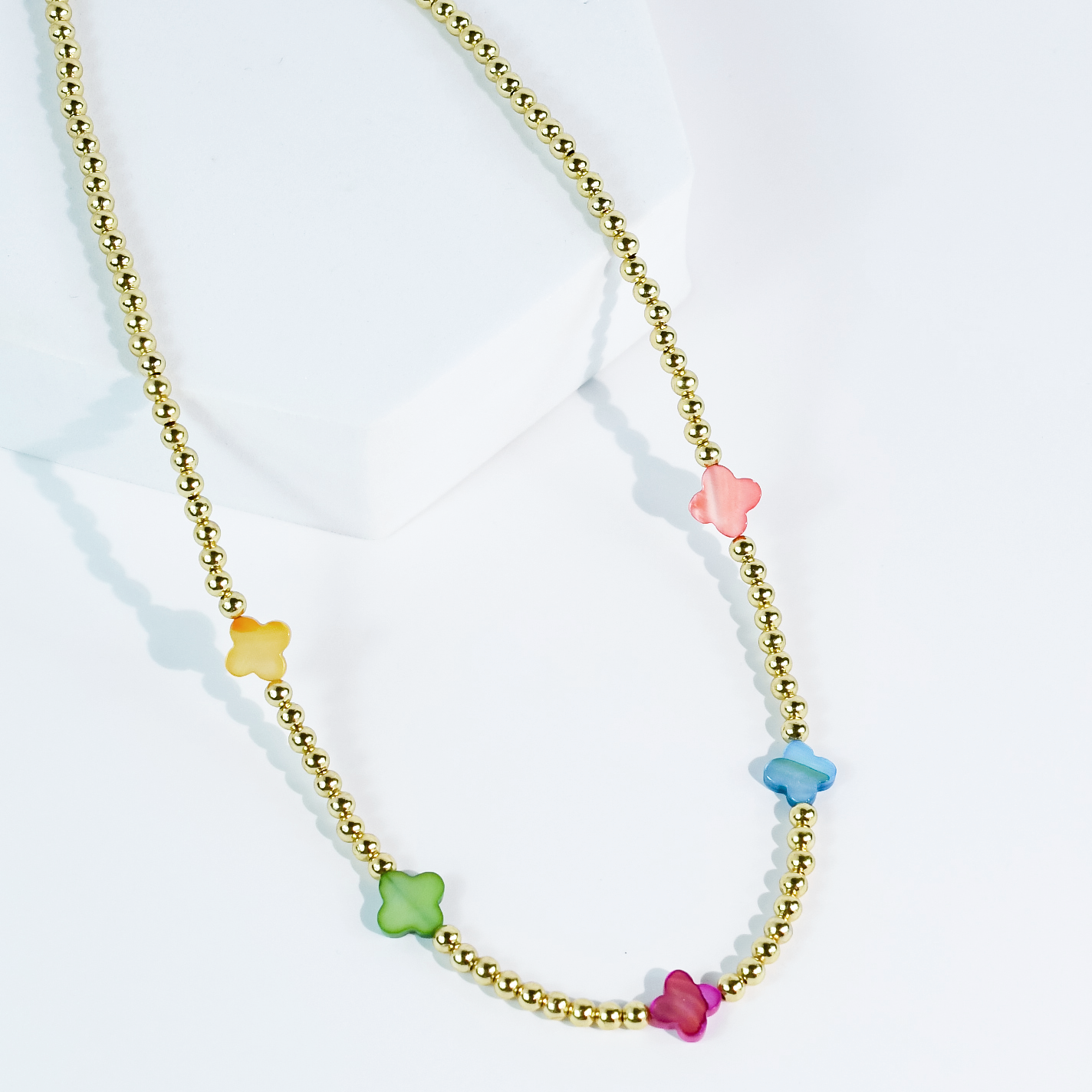 The Petal Pop Necklace by Treasure Jewels with gold and pastel flower beads in yellow, green, blue, pink, and red. Sizes available.