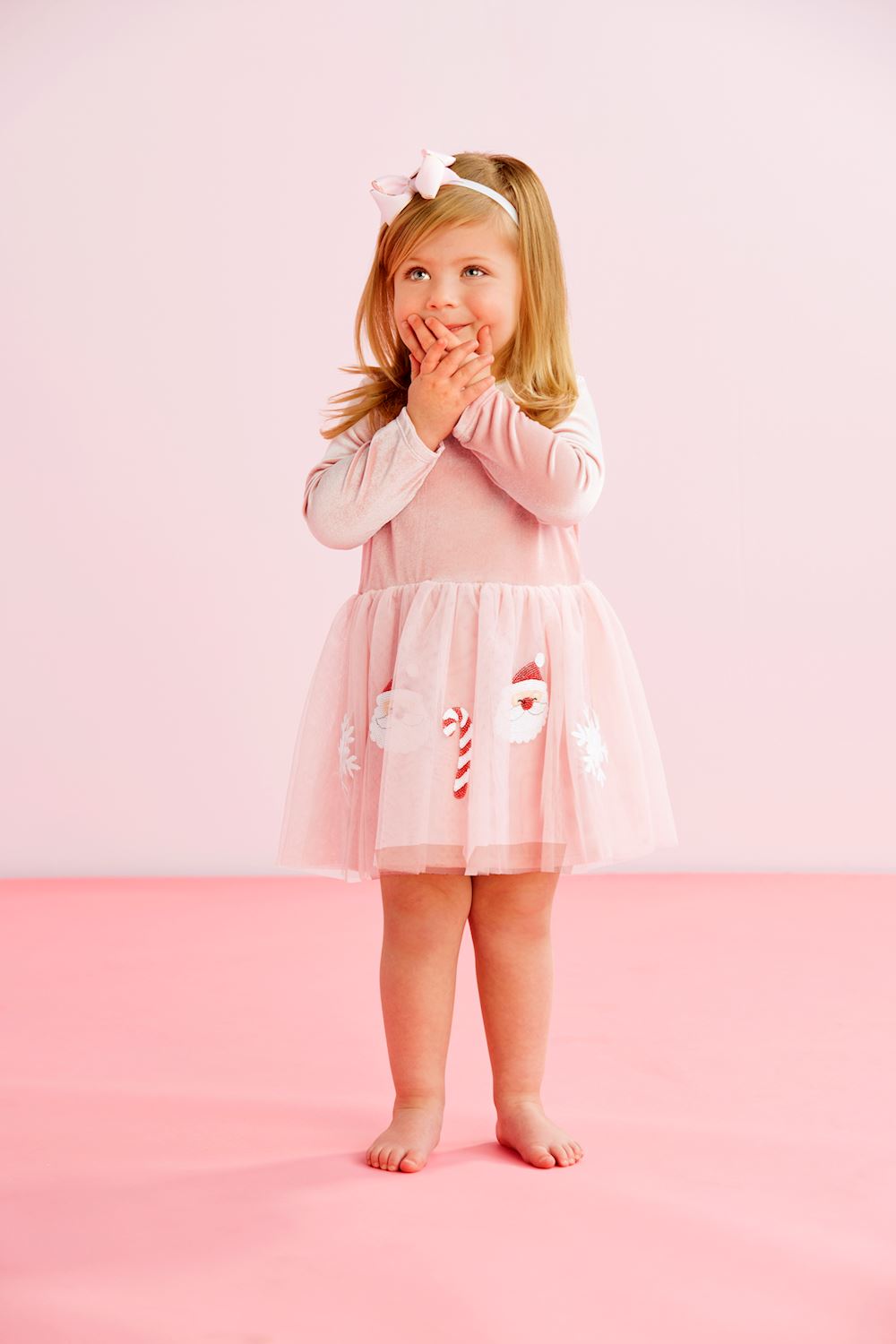 Pink sequin tutu dress with long sleeves, pink velour bodice, and mesh skirt with Santa and candy cane appliqués. Available in various sizes.