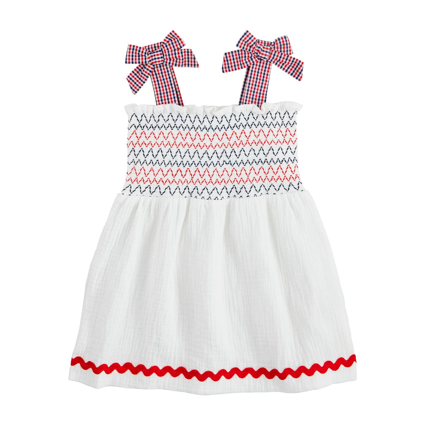 The White Smocked Gauze Toddler Dress is a charming cotton outfit with smocked zigzag patterns in red and navy, gingham bow straps in red and blue checks, and a red wavy hem trim. Available sizes: 12M, 18M, 24M, 2T, 3T.
