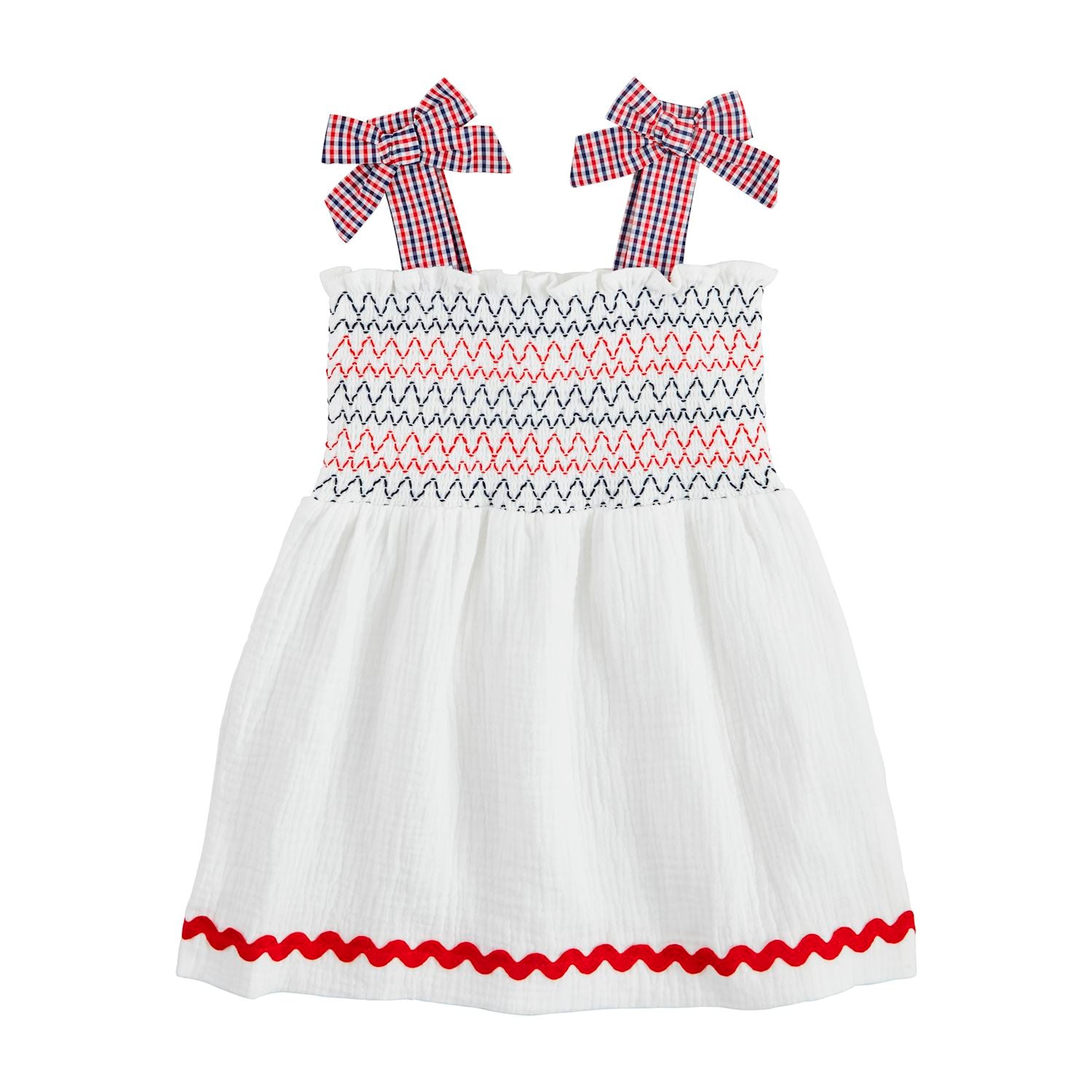 The White Smocked Gauze Toddler Dress is a charming cotton outfit with smocked zigzag patterns in red and navy, gingham bow straps in red and blue checks, and a red wavy hem trim. Available sizes: 12M, 18M, 24M, 2T, 3T.