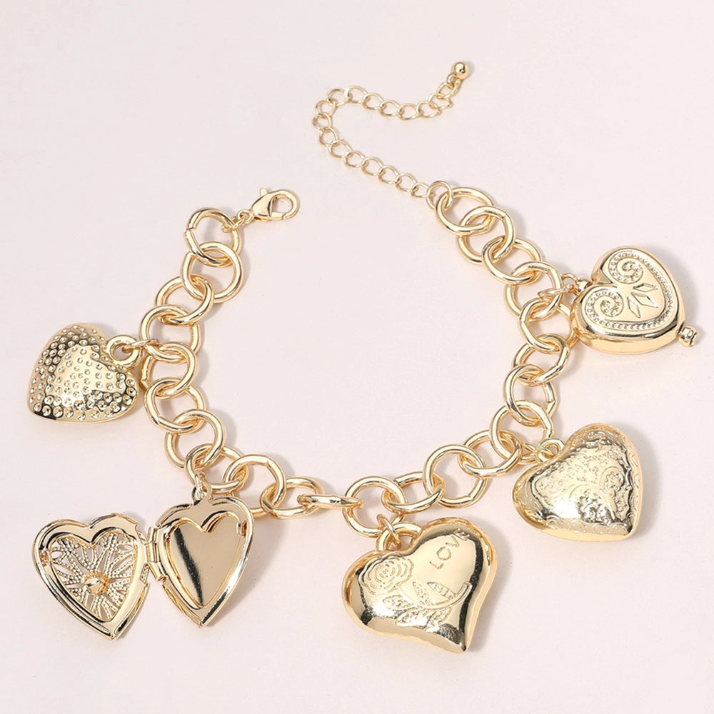 The Heart Locket Metal Heart Charm Station Chain Bracelet showcases gold heart-shaped pendants with intricate designs, including textured and open styles. It features a lobster clasp and an adjustable chain. Sizes: Adjustable length.