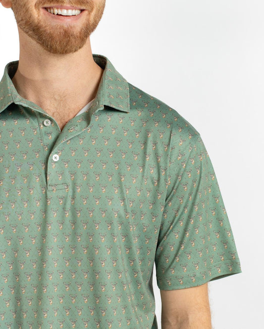 Men’s Bow Hunting Performance Polo in green with repeating deer heads and crossed antlers pattern. Available in sizes S-XXL.