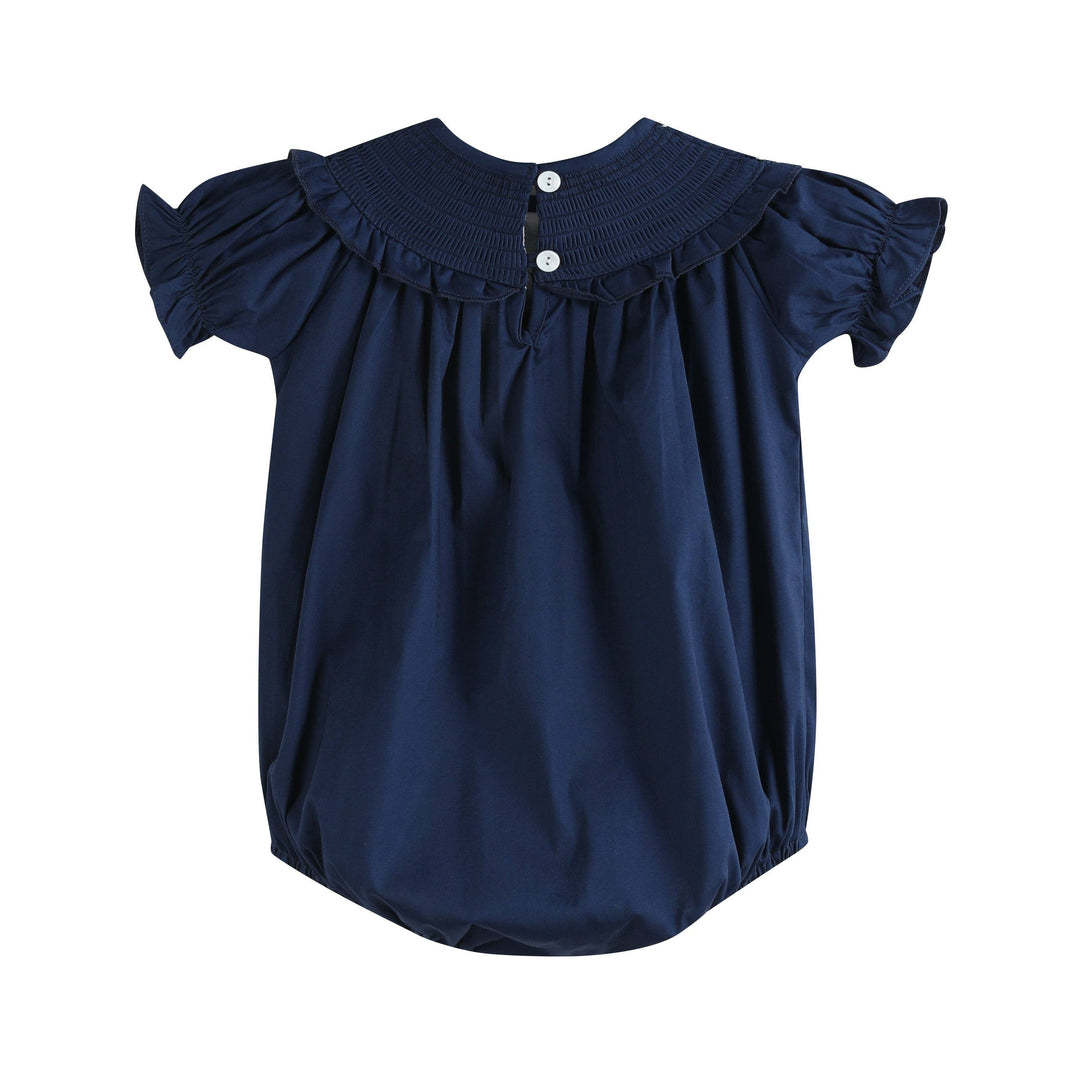 Navy Blue Nativity Smocked Ruffle Romper with short ruffled sleeves, pleated collar, white back buttons, and gathered lightweight fabric at neckline and leg openings. Available in size 2T.