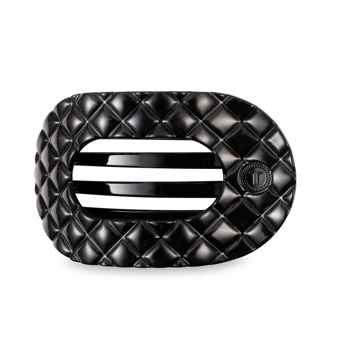Black oval TELETIES Flat Round Hair Clip with quilted pattern, slats, "T" emblem; available in large and small sizes.