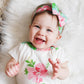 baby modeling onesie and headband laying on a faux fur rug. Baby is smiling.