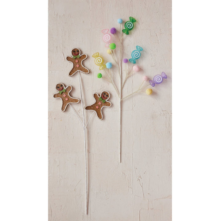Two decorative holiday sprays: one with three gingerbread cookie figures, one with colorful candy ornaments and pom-poms.
