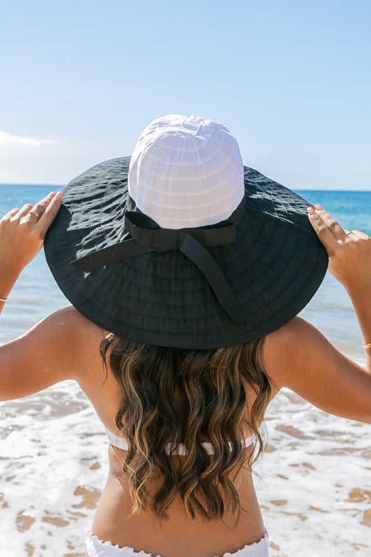 Classic Bow Accent Sunhat: Wide-brimmed sunhat in natural straw with a white bow accent. Provides UPF 50+ sun protection. Adjustable inner band for a secure fit. Sizes available: S, M, L.