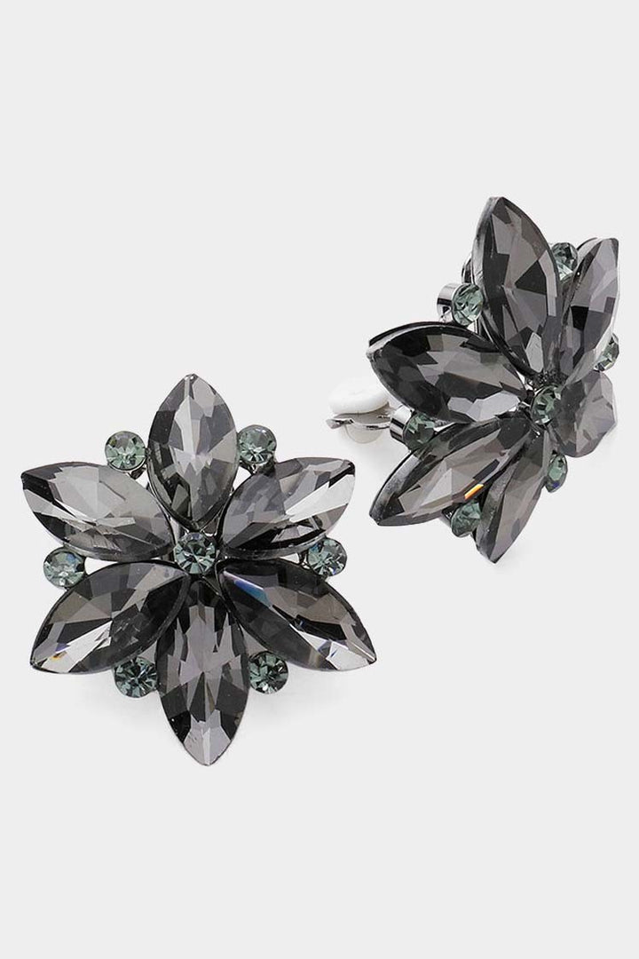 Glass Stone Flower Clip On Evening Earrings. Shaped like flowers with six large, dark gray, faceted stones forming the petals. Accented with smaller, round, dark gray stones at center and edges. Reflective, shiny surface for added sophistication. Sizes available: one size fits all.

