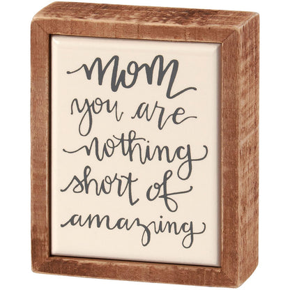 The Mini Mom Amazing Box Sign is a decorative wooden box with the phrase "Mom, you are nothing short of amazing" in black cursive on a white background. Available size: 5" x 3".