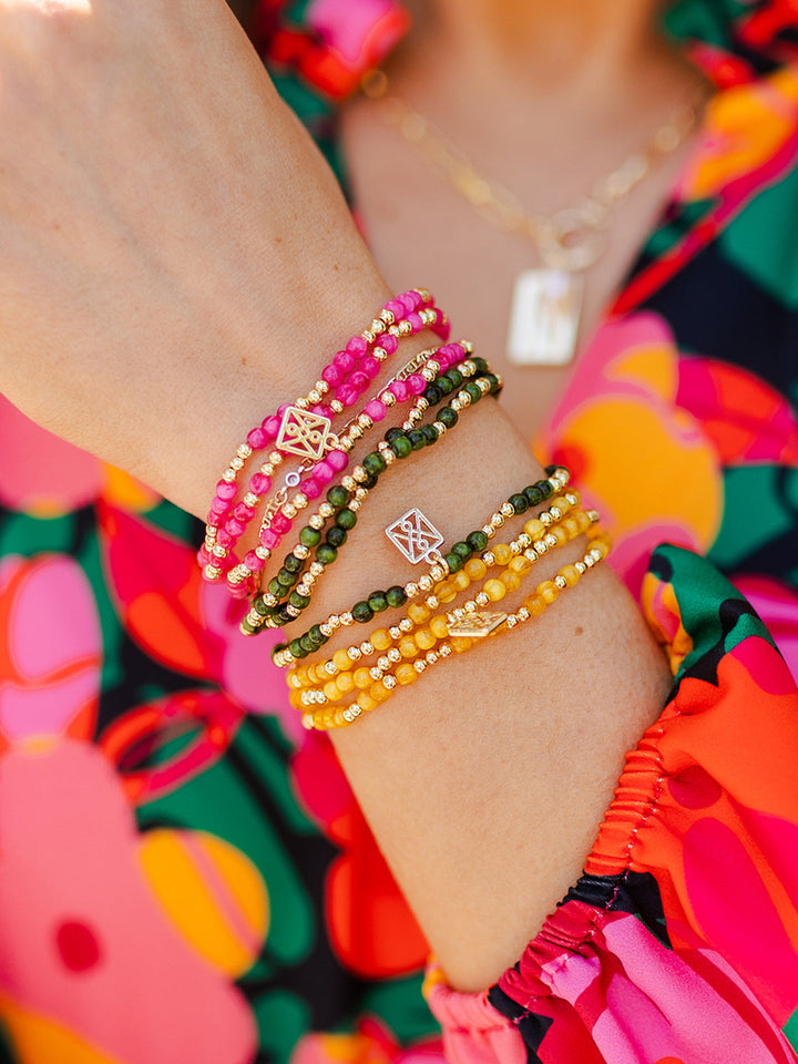 Colorful Bracelet Bar pieces in pink, green, and yellow with gold charms shown. Available in S, M, L.