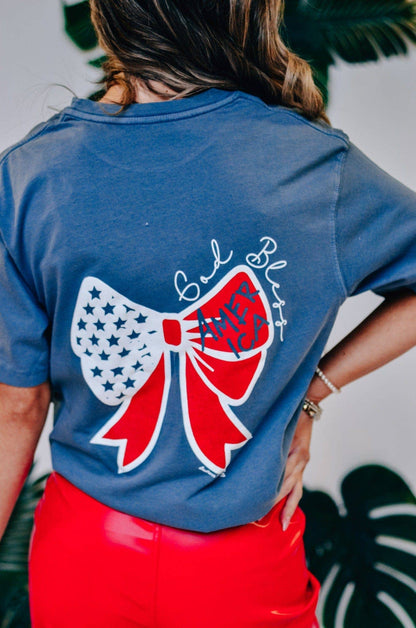 Denim blue God Bless America Bow Tee with red, white, and blue bow print and "God Bless America" on back. Sizes S-XL.