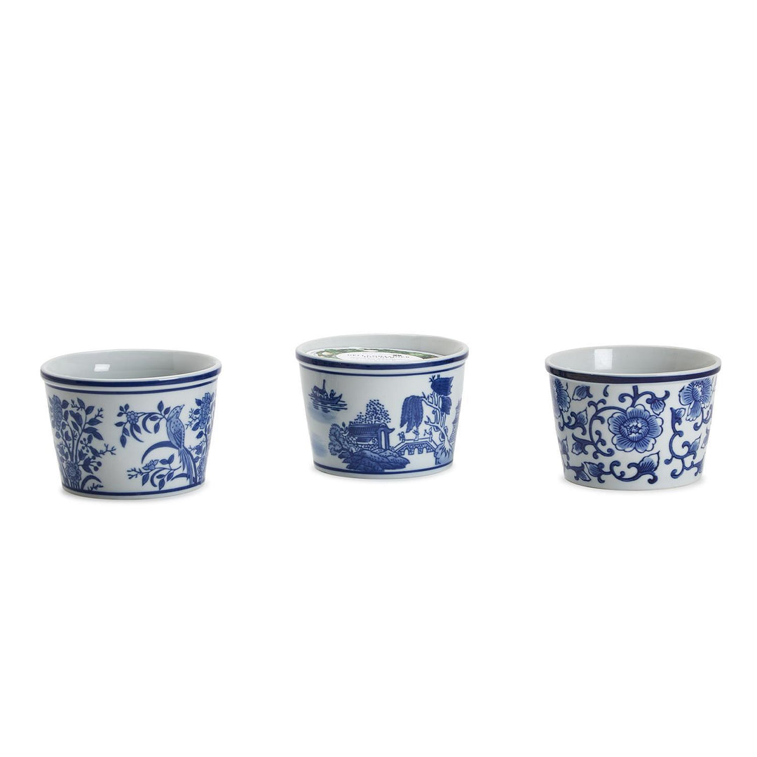 Three blue and white ceramic cups with floral and landscape designs on a white background