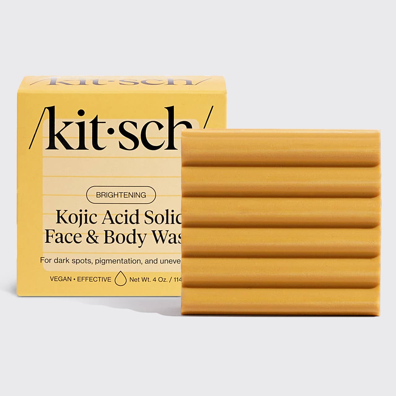 Yellow rectangular Kojic Acid soap bar with horizontal grooves. Black text packaging. Available in multiple sizes.