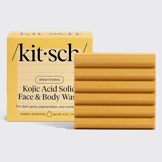 Yellow rectangular Kojic Acid soap bar with horizontal grooves. Black text packaging. Available in multiple sizes.