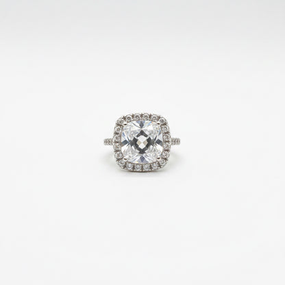 Midgle Silver Crystal Statement Ring with a cushion-cut crystal, halo of smaller stones, pavé band, and silver-tone finish. Available in sizes 6-9.