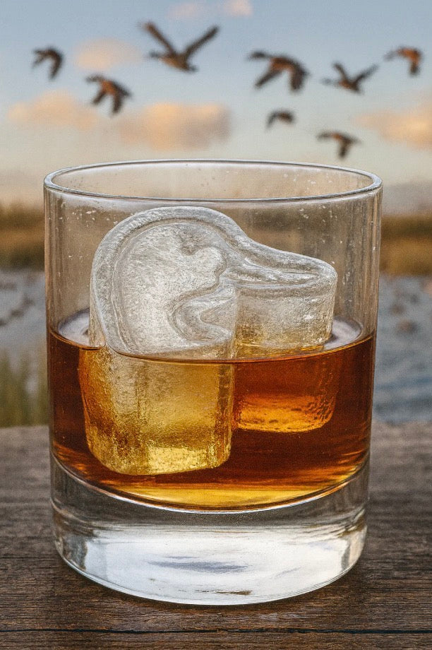 A glass of whiskey with two ice cubes, including one shaped like a duck’s head using the Ducks Unlimited Ice Mold, available in standard and large sizes.