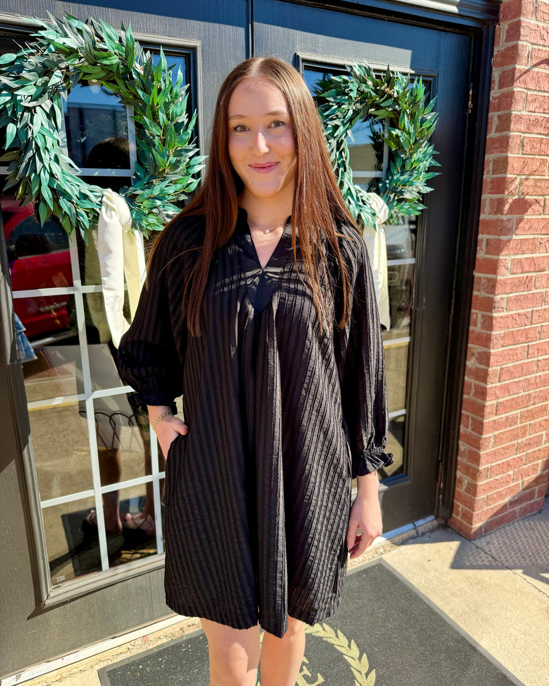Black knee-length V-neck shift dress with long sleeves and textured vertical stripes.