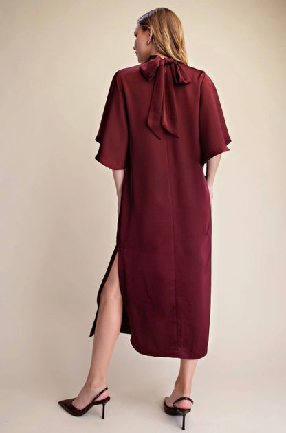 Satin Tie Back Midi Dress in burgundy with short sleeves, back bow detail, and side slit. Available in sizes XS-XL.