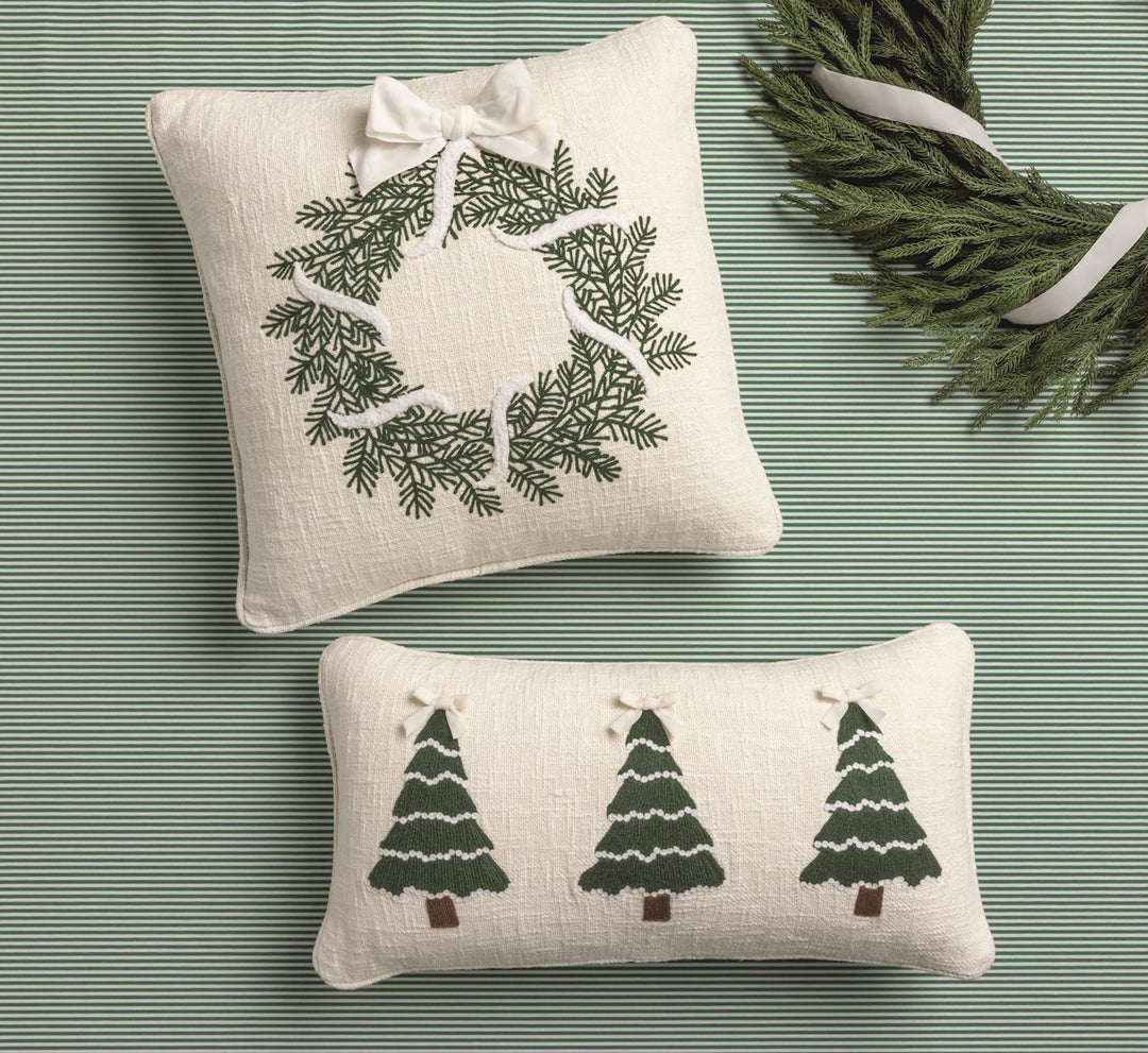 White velvet lumbar pillow with three embroidered green Christmas trees and white bows.