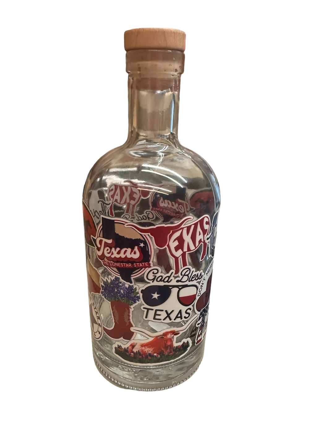 Clear glass bottle with wooden cork, decorated with Texas-themed stickers (state images, "Texas," "God Bless Texas," cowboy boots, cactus). Sizes available: 16 oz, 32 oz.