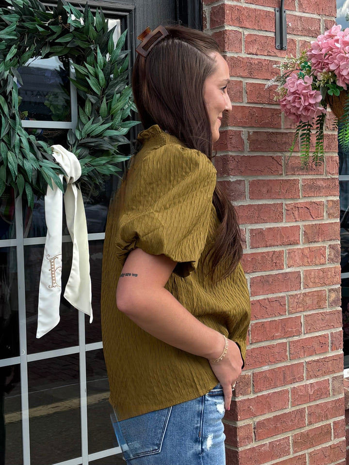 Olive Ruffled Blouse in textured fabric with a relaxed silhouette. Available in sizes XS–XL.