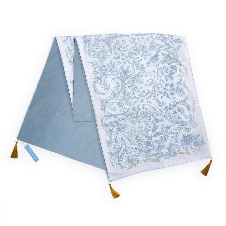 Gilded Cottage Double-Sided Table Runner with blue and white bird and botanical print, solid blue reverse, and gold corner tassels. Available in multiple sizes.