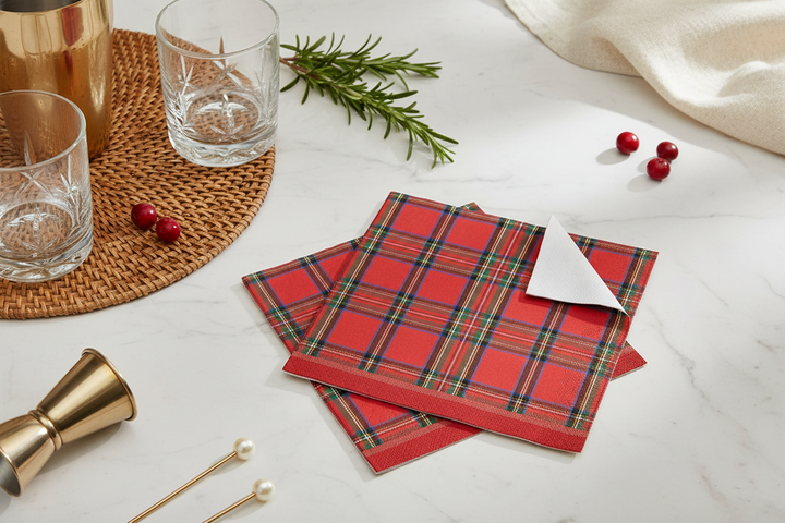 Two square tartan paper cocktail napkins with a red, green, and blue plaid pattern.