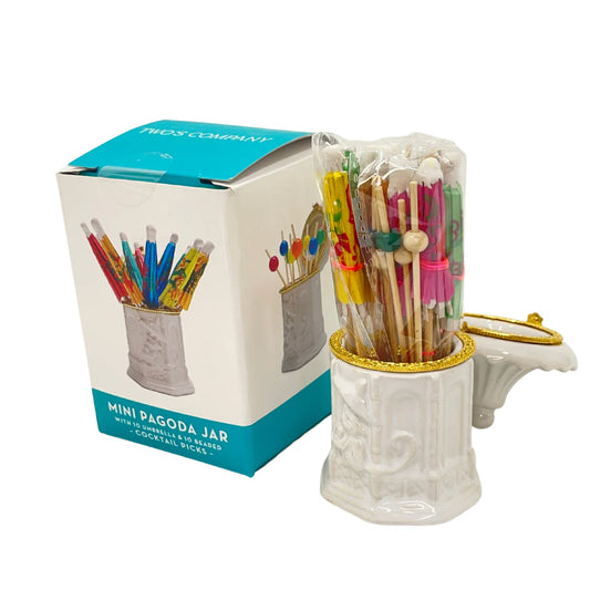 A white ceramic Mini Pagoda Jar with Umbrella & Bead Cocktail Picks next to its packaging box, containing colorful cocktail sticks with decoratively designed tops. This reusable jar is perfect for hosting essentials.