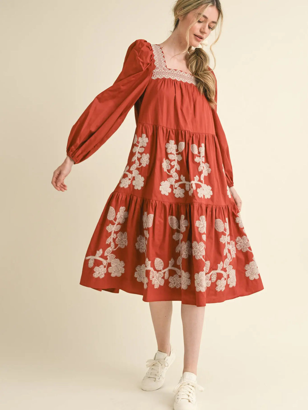 Rust tiered midi dress with long sleeves, square neckline, and cream boho floral embroidery. Available in all sizes.