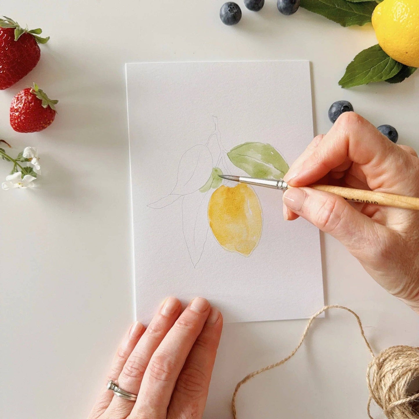 Fruit paintable watercolor notecard set with a hand painting a lemon and leaf on white paper. Available in standard 4x6 and 5x7 inch sizes.