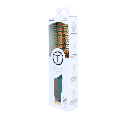 Boxed “Vented Hair Brush - Teal With It” with a teal handle and patterned, anti-static bristles, visible through a circular cutout. Available in standard size.