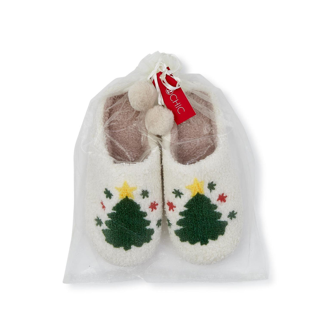 Cream plush slippers with green Christmas tree and yellow star pattern in a sheer drawstring bag.