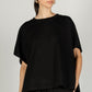 A woman with her hair pulled back wears a P. CILL Butter Modal Side Slit Cape Top paired with matching black pants, showcasing the sizing.