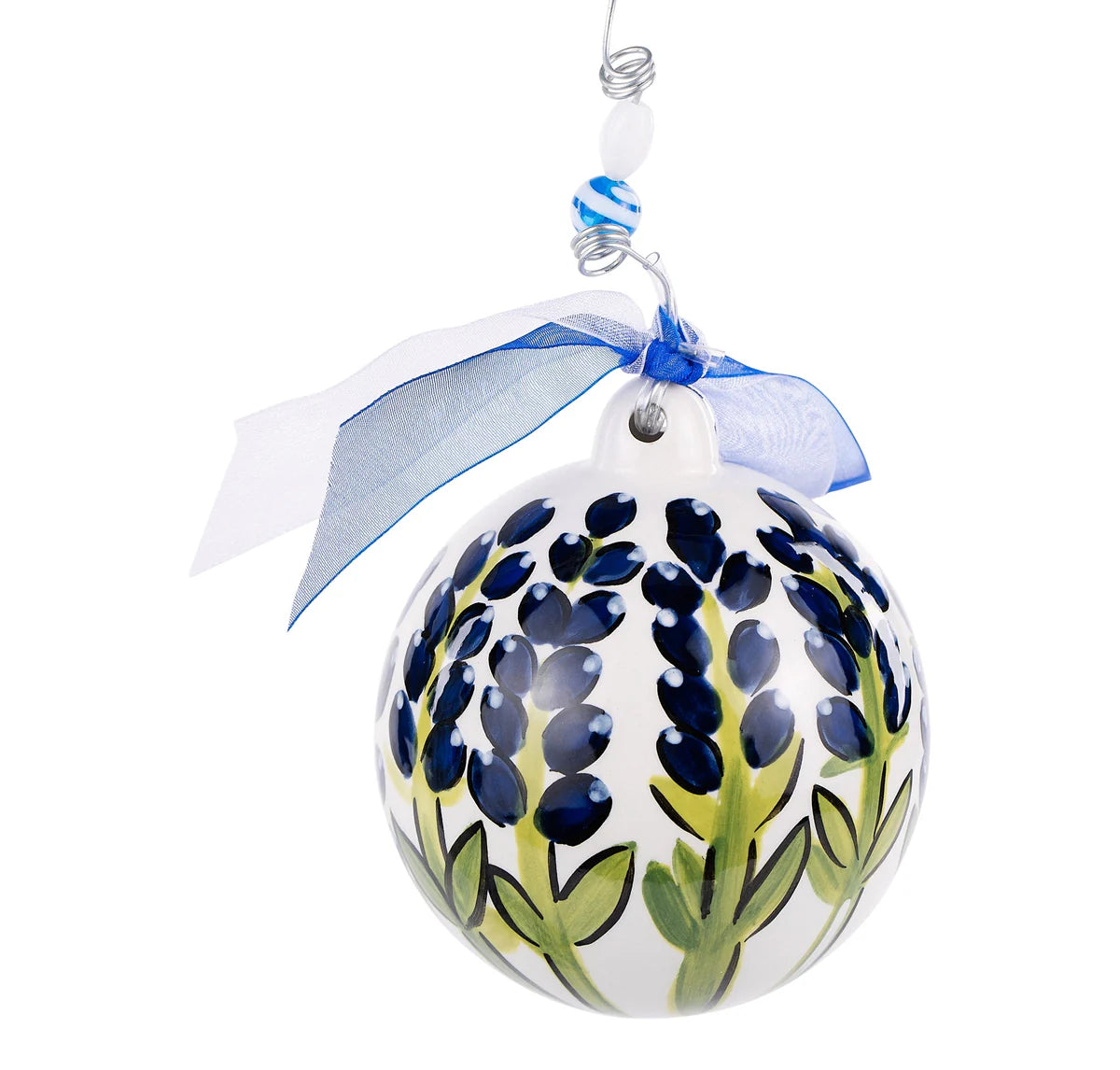 The Blue Bonnet Ornament is a round ceramic piece, hand-painted with intricate bluebonnet flowers. It hangs from a silver wire and bead hook, accented by a blue ribbon. Sizes: N/A.