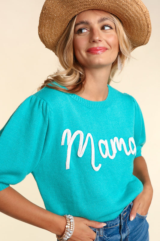 A woman in a bright turquoise Mama Embroidered Pop Letter Short Bubble Sleeve Sweater - Plus, smiling playfully while looking to the side, on a beige background.