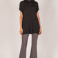 A woman wears a stylish outfit featuring a Super Rayon Jersey Cowl Neck Tunic with a draped neckline and gray flared pants, paired with black open-toe heels. Sizing options are available.